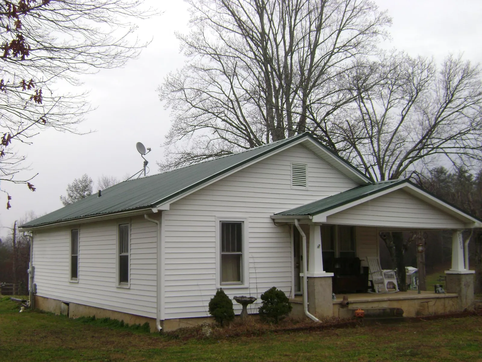 Green metal roof on a white bungalow with a side porch in Sterling